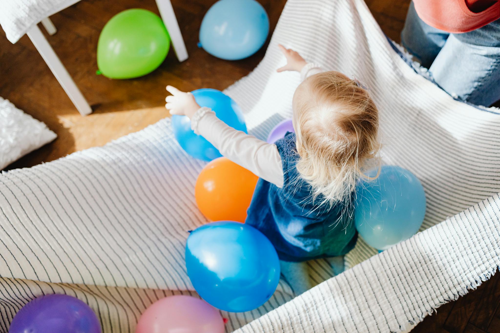 A toddler enjoying playtime with vibrant balloons indoors, creating a joyful scene.