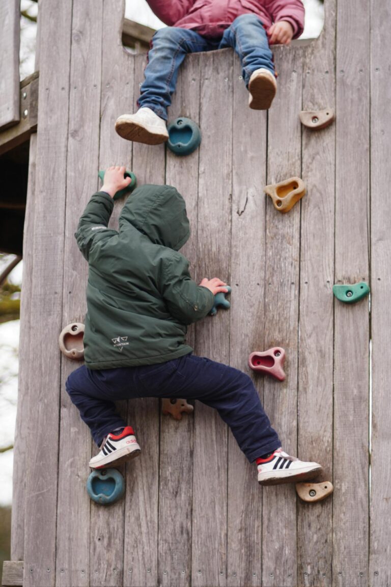 Kids enjoying a climbing wall adventure at an outdoor playground, fostering fun and fitness.