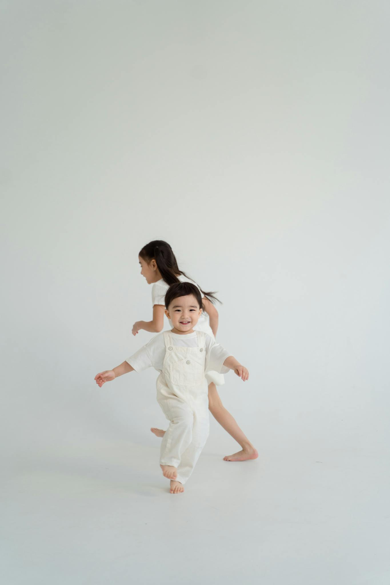 Two children run and play joyfully in a serene and minimalist background.